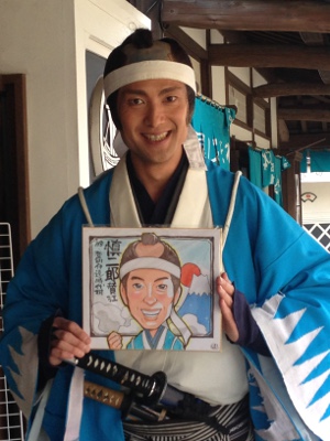 お侍さんがそっくりな似顔絵を持っている写真